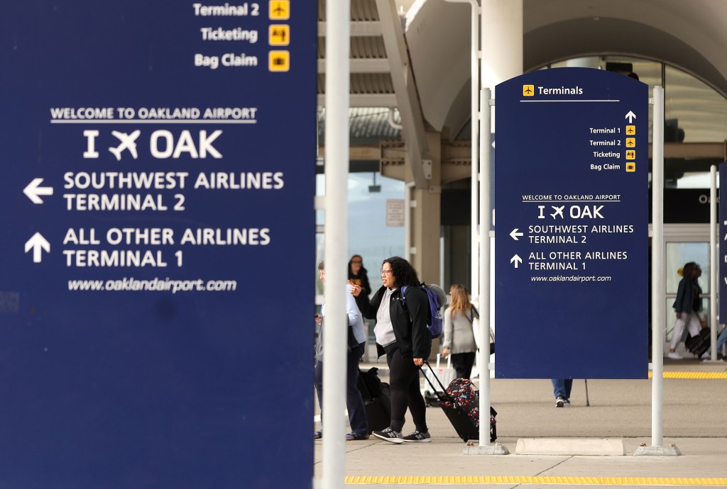 Travelers walk with luggage in Terminal 1 at Oakland International Airport, soon to be San Francisco Bay Oakland International Airport